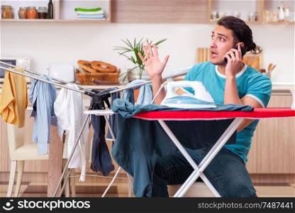 The young man husband doing clothing ironing at home. Young man husband doing clothing ironing at home