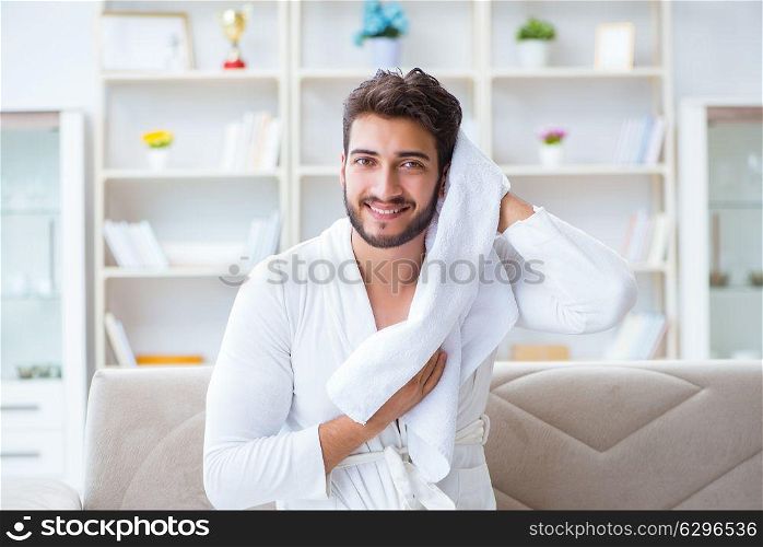 The young man in a bathrobe after shower drying hair with a towel. Young man in a bathrobe after shower drying hair with a towel
