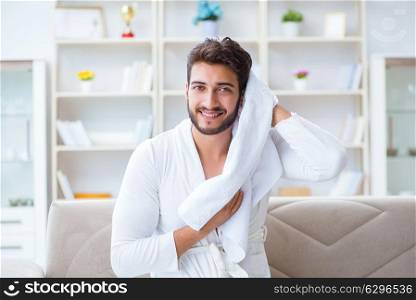 The young man in a bathrobe after shower drying hair with a towel. Young man in a bathrobe after shower drying hair with a towel