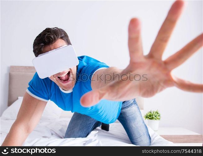 The young man in bed wearing a vr virtual reality head set. Young man in bed wearing a vr virtual reality head set