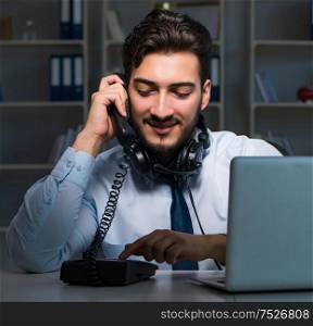 The young man in call center concept working late overtime in office. Young man in call center concept working late overtime in office