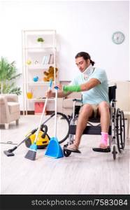 The young man in wheel-chair cleaning the house. Young man in wheel-chair cleaning the house