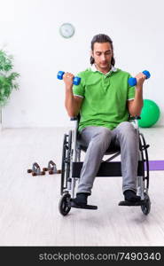 The young man in wheel-chair doing exercises indoors. Young man in wheel-chair doing exercises indoors