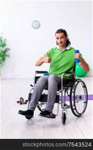 The young man in wheel-chair doing exercises indoors. Young man in wheel-chair doing exercises indoors