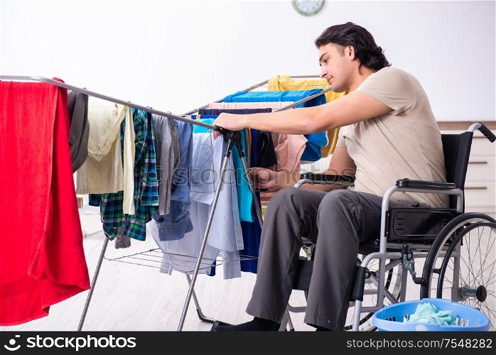 The young man in wheel-chair doing ironing at home. Young man in wheel-chair doing ironing at home