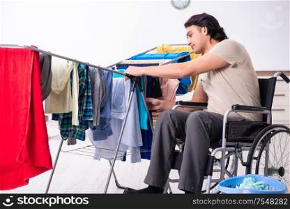 The young man in wheel-chair doing ironing at home. Young man in wheel-chair doing ironing at home