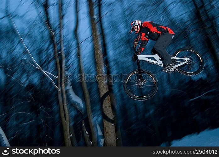 The young man jumps on a bicycle from a springboard