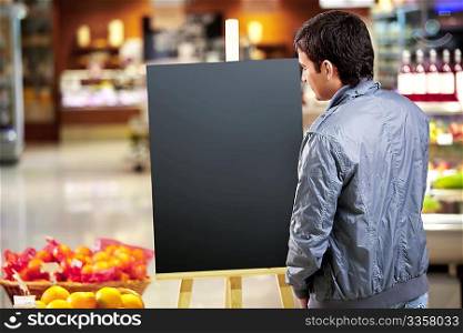 The young man looks at an empty board in shop