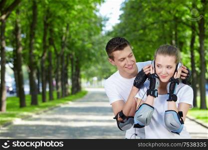 The young man looks at the girl listening to music in ear-phones in park