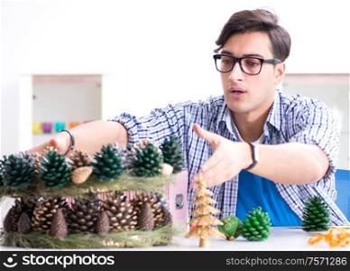 The young man making christmas decoration from cones. Young man making christmas decoration from cones