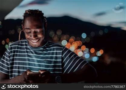 The young man on an urban city street at night texting on a smartphone with bokeh and neon city lights in the background. High-quality photo. High-quality photo. The young man on an urban city street at night texting on smartphone with bokeh and neon city lights in the background. 
