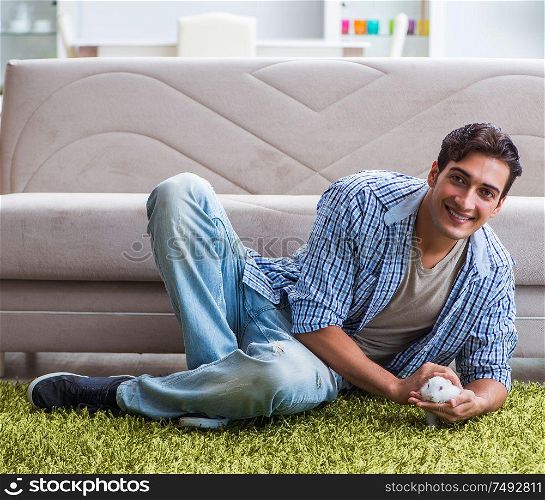 The young man playing with pet rabbit at home. Young man playing with pet rabbit at home