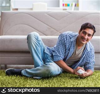 The young man playing with pet rabbit at home. Young man playing with pet rabbit at home