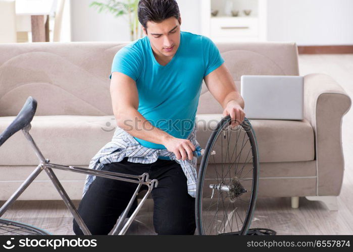 The young man repairing bicycle at home. Young man repairing bicycle at home