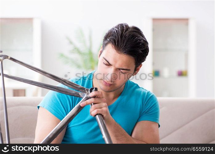 The young man repairing bicycle at home. Young man repairing bicycle at home