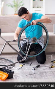 The young man repairing bicycle at home. Young man repairing bicycle at home