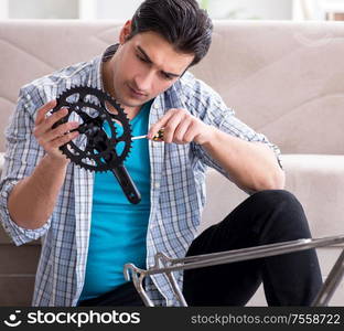 The young man repairing bicycle at home. Young man repairing bicycle at home