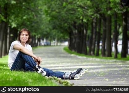 The young man sits on a grass with rollers