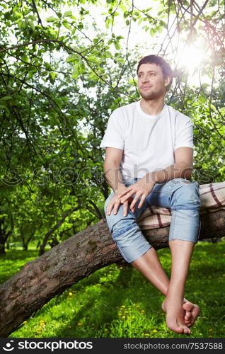 The young man sits on a tree