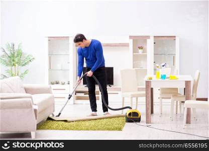 The young man vacuum cleaning his apartment. Young man vacuum cleaning his apartment