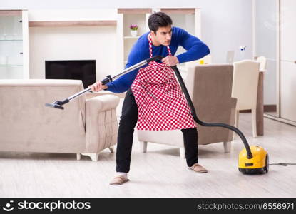 The young man vacuum cleaning his apartment. Young man vacuum cleaning his apartment