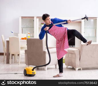 The young man vacuum cleaning his apartment. Young man vacuum cleaning his apartment