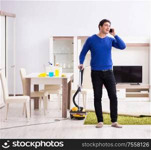 The young man vacuum cleaning his apartment. Young man vacuum cleaning his apartment