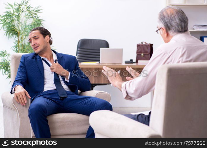 The young man visiting old male doctor psychologist. Young man visiting old male doctor psychologist