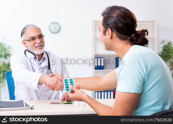 The young man visiting old male doctor. Young man visiting old male doctor