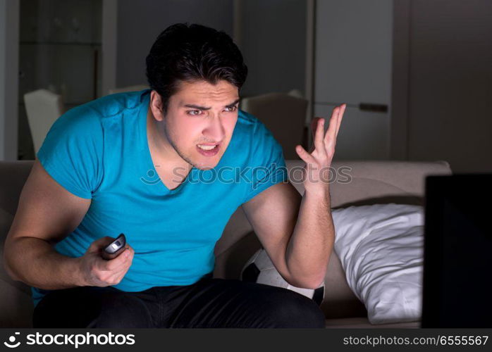 The young man watching football late at night. Young man watching football late at night