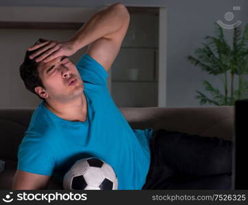 The young man watching football late at night. Young man watching football late at night