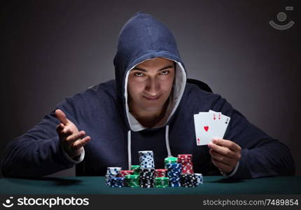 The young man wearing a hoodie with cards and chips gambling. Young man wearing a hoodie with cards and chips gambling