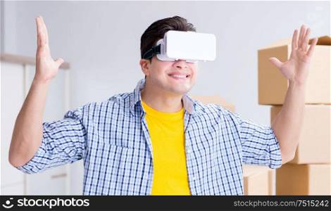 The young man wearing vr glasses moving in new apartment. Young man wearing VR glasses moving in new apartment