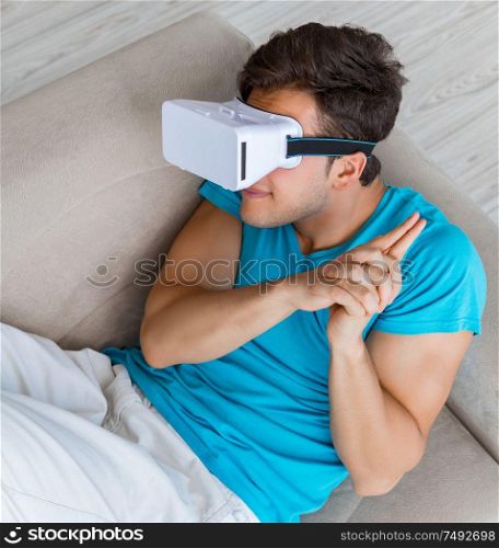 The young man wearing vr glasses relaxing on couch sofa. Young man wearing VR glasses relaxing on couch sofa