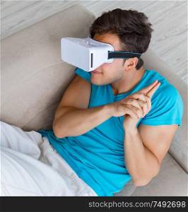 The young man wearing vr glasses relaxing on couch sofa. Young man wearing VR glasses relaxing on couch sofa