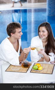 The young man with tea and attractive girl in pool