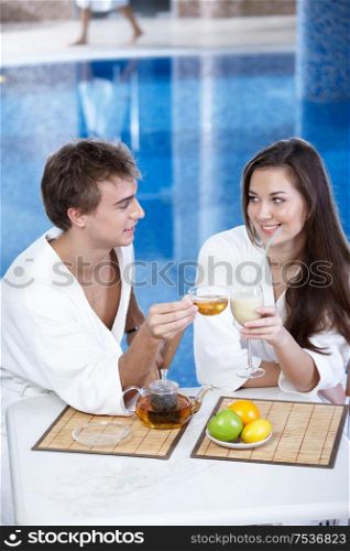 The young man with tea and attractive girl in pool