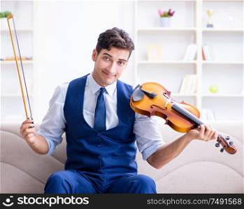 The young musician man practicing playing violin at home. Young musician man practicing playing violin at home