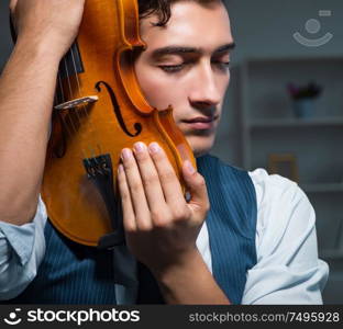 The young musician man practicing playing violin at home. Young musician man practicing playing violin at home