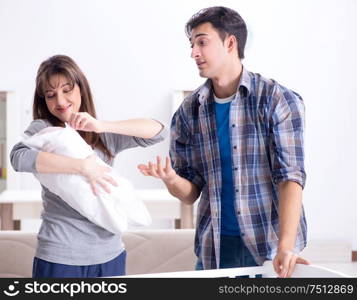 The young parents with their newborn baby near bed cot. Young parents with their newborn baby near bed cot