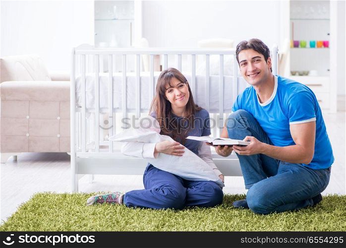The young parents with their newborn baby sitting on the carpet . Young parents with their newborn baby sitting on the carpet