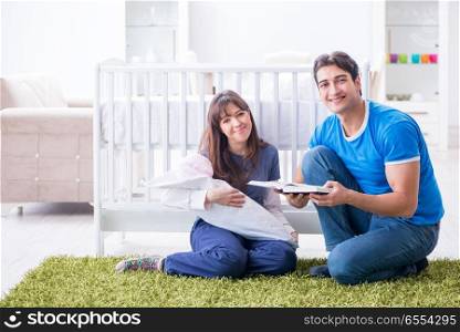 The young parents with their newborn baby sitting on the carpet . Young parents with their newborn baby sitting on the carpet