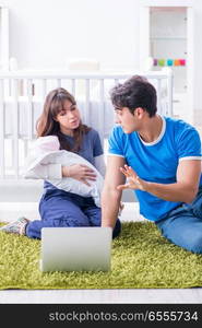 The young parents with their newborn baby sitting on the carpet . Young parents with their newborn baby sitting on the carpet