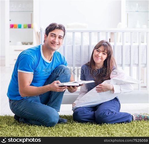 The young parents with their newborn baby sitting on the carpet. Young parents with their newborn baby sitting on the carpet