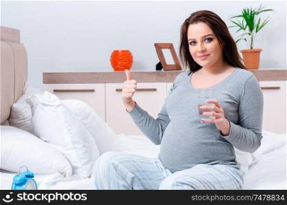The young pregnant woman in the bedroom . Young pregnant woman in the bedroom