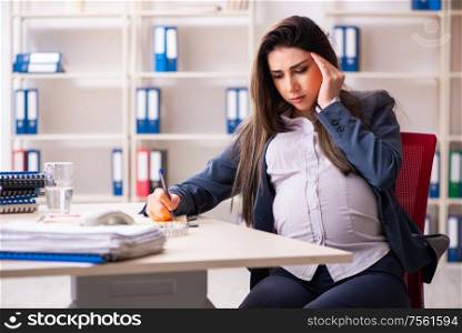 The young pregnant woman working in the office. Young pregnant woman working in the office