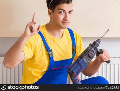 The young repairman contractor repairing heating panel. Young repairman contractor repairing heating panel