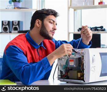 The young repairman fixing and repairing microwave oven. Young repairman fixing and repairing microwave oven