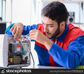 The young repairman fixing and repairing microwave oven. Young repairman fixing and repairing microwave oven