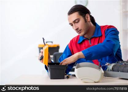 The young repairman repairing air-conditioner at warranty center. Young repairman repairing air-conditioner at warranty center